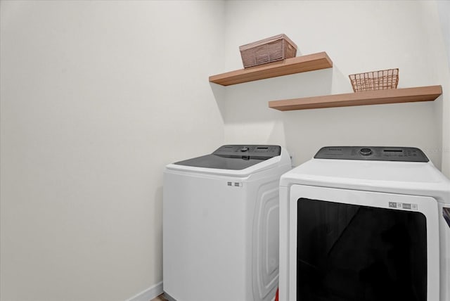 clothes washing area with laundry area, washer and clothes dryer, and baseboards