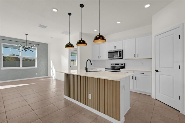 kitchen with visible vents, decorative backsplash, an island with sink, stainless steel appliances, and a sink