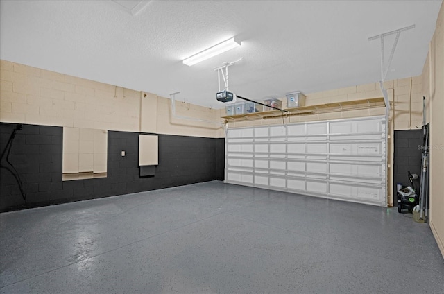 garage featuring a garage door opener and concrete block wall