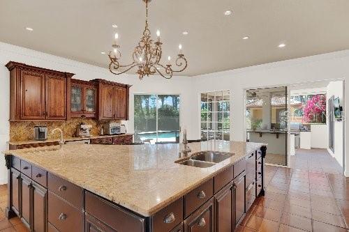 kitchen with a large island, light stone countertops, tasteful backsplash, and a sink