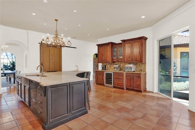 kitchen featuring beverage cooler, a sink, backsplash, arched walkways, and a chandelier