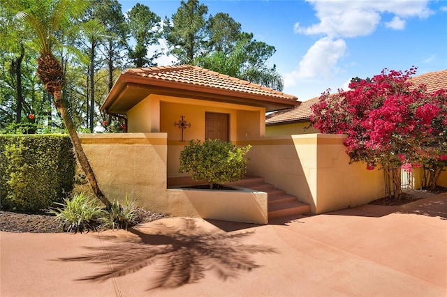 view of front of property with a patio area, a tile roof, fence, and stucco siding