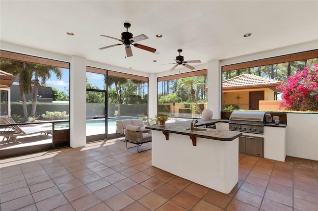 interior space with a fenced in pool, an outdoor kitchen, a sink, ceiling fan, and a grill