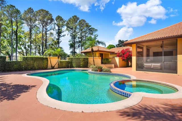 view of swimming pool featuring a pool with connected hot tub, a patio, and fence