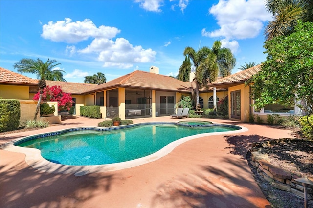 view of swimming pool featuring a pool with connected hot tub, a patio area, and a sunroom