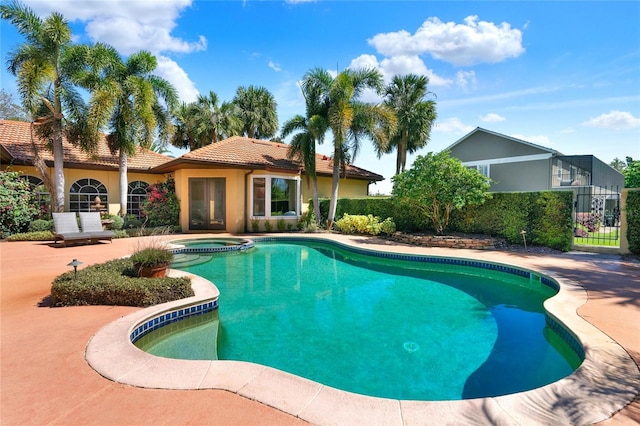 view of swimming pool with a patio, fence, and a pool with connected hot tub