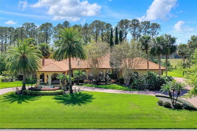 view of front of home with stucco siding, a tile roof, and a front yard