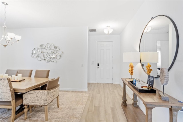 dining room featuring baseboards, visible vents, a chandelier, and light wood-type flooring