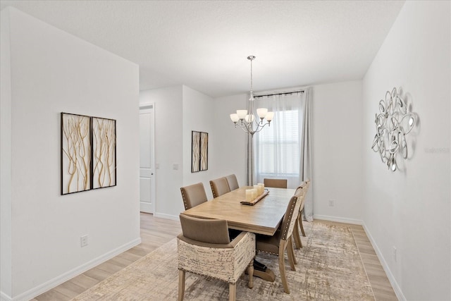 dining area featuring an inviting chandelier, baseboards, and light wood finished floors