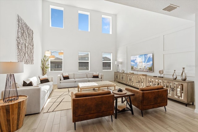 living room with light wood finished floors, visible vents, and a decorative wall