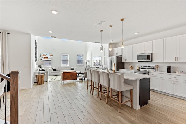 kitchen featuring open floor plan, a kitchen breakfast bar, light wood-type flooring, and appliances with stainless steel finishes