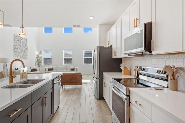 kitchen with a sink, appliances with stainless steel finishes, open floor plan, and light countertops