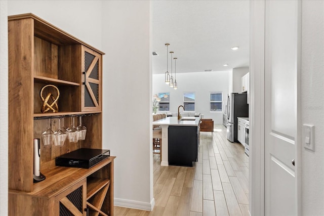 hallway with a sink, baseboards, and wood tiled floor