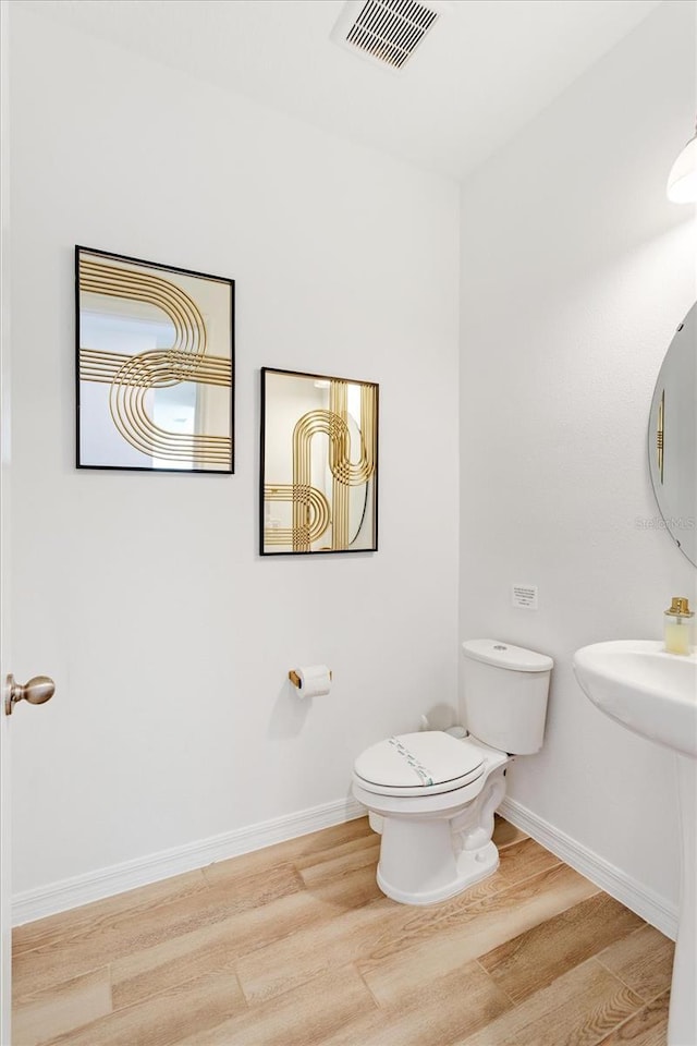 bathroom with visible vents, baseboards, toilet, and wood finished floors