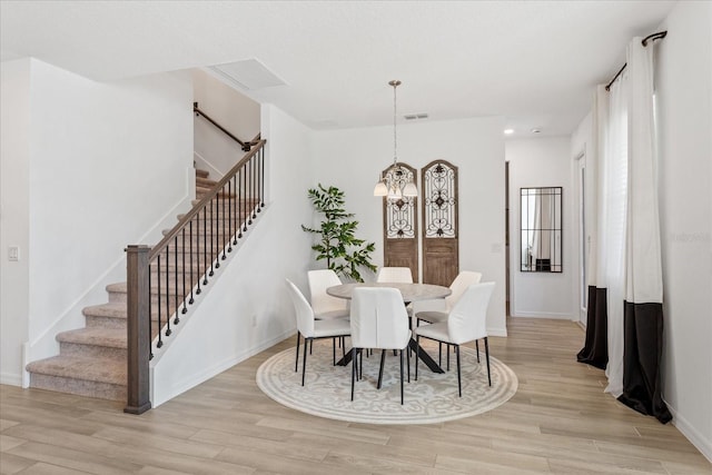 dining space featuring stairway, baseboards, visible vents, an inviting chandelier, and light wood-style flooring