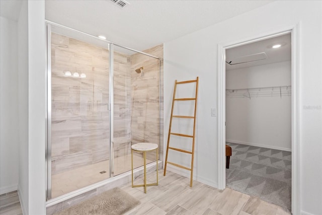 bathroom featuring a walk in closet, baseboards, visible vents, and a stall shower