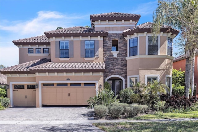 mediterranean / spanish-style home with decorative driveway, stone siding, and stucco siding