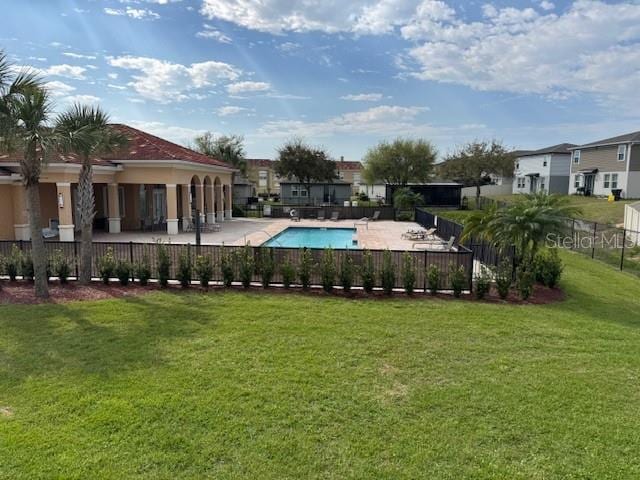 community pool with a patio area, fence, and a yard