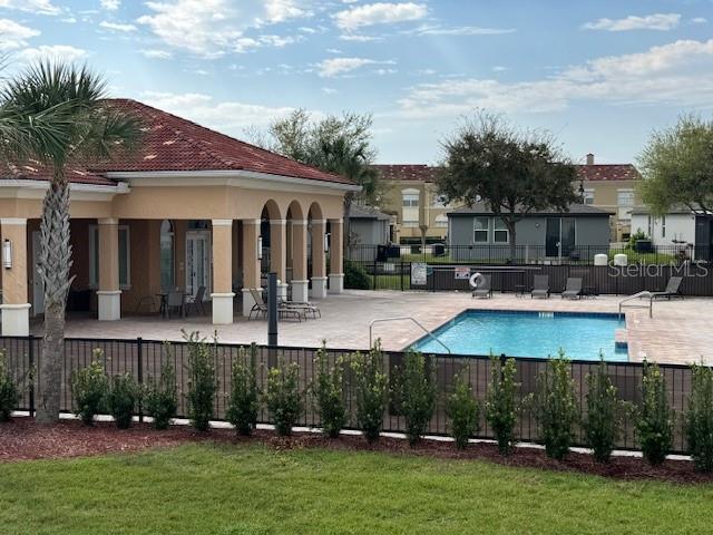 community pool with a patio area and fence