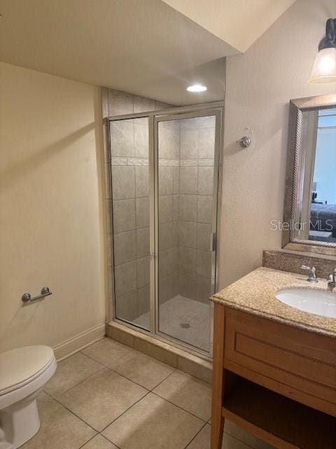 bathroom featuring toilet, a stall shower, vanity, tile patterned flooring, and baseboards