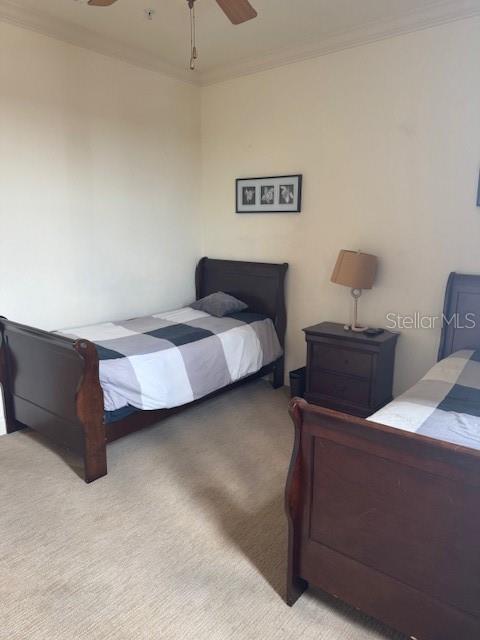 carpeted bedroom with ornamental molding and a ceiling fan