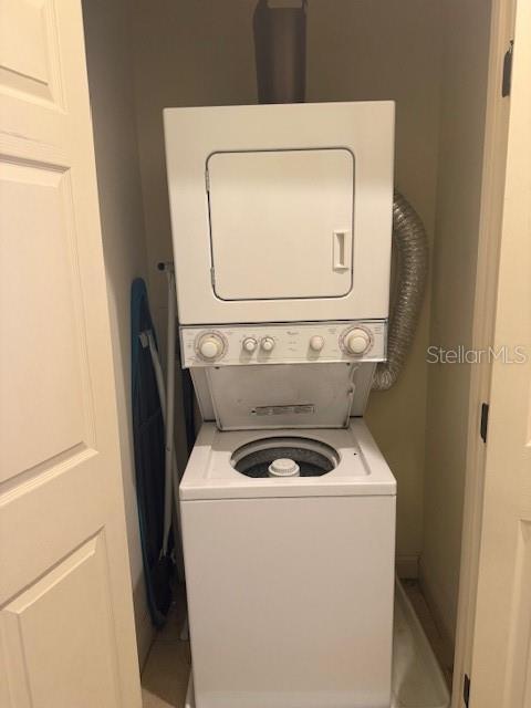 clothes washing area with stacked washing maching and dryer and laundry area