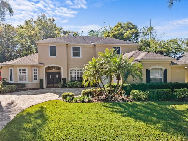 mediterranean / spanish home with stucco siding, driveway, and a front yard