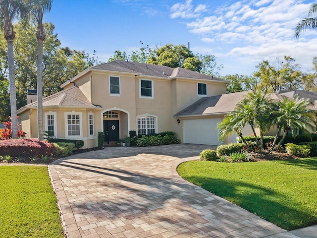 view of front of house with stucco siding, decorative driveway, a garage, and a front yard