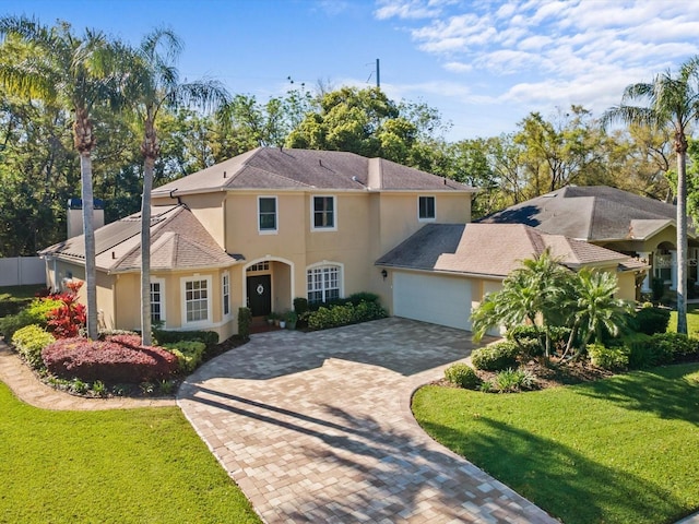 view of front of property with stucco siding, decorative driveway, a garage, and a front lawn