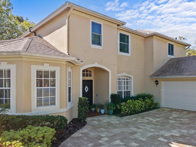 view of front facade featuring an attached garage, driveway, and stucco siding