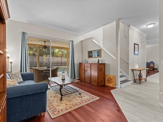 living room featuring crown molding, stairway, light wood-style flooring, and baseboards