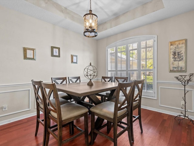 dining room featuring a tray ceiling, an inviting chandelier, wood finished floors, and wainscoting