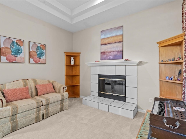 living area featuring carpet floors, a raised ceiling, and a tiled fireplace