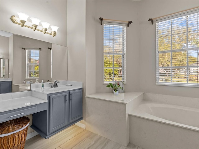 full bath with a bath, a healthy amount of sunlight, vanity, and wood finished floors