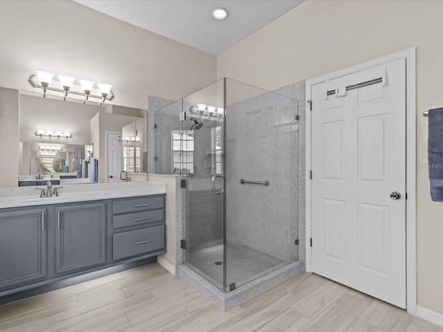 full bathroom with vanity, an inviting chandelier, a stall shower, and wood tiled floor