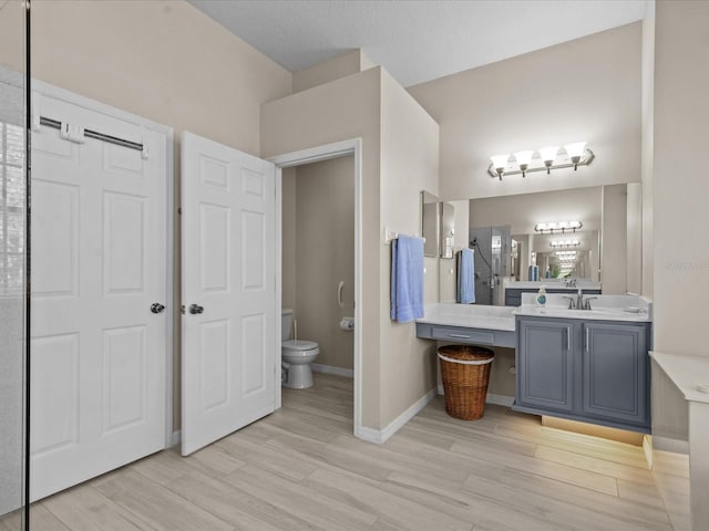 full bathroom with vanity, toilet, wood finished floors, and baseboards