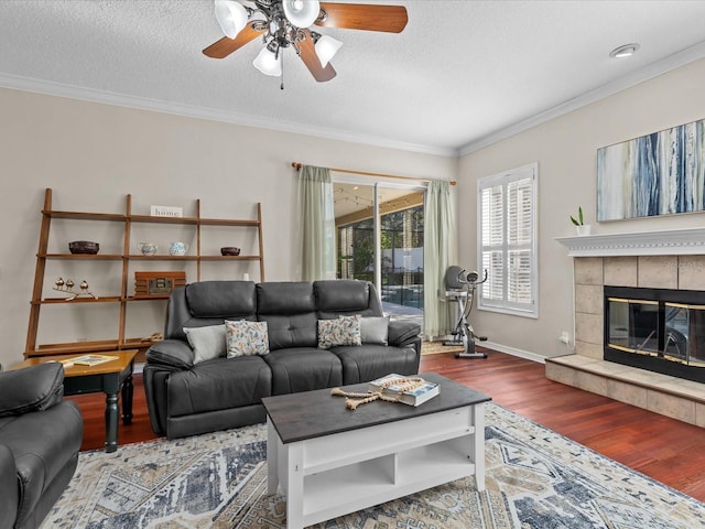 living area featuring a textured ceiling, wood finished floors, a ceiling fan, and crown molding