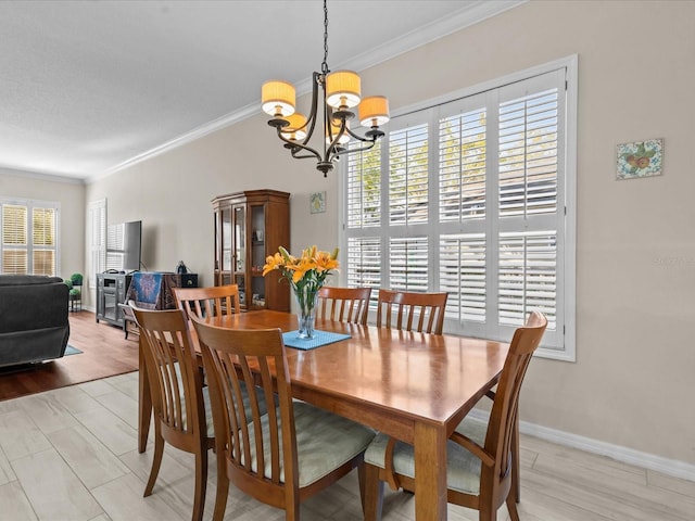 dining room with a chandelier, light wood-style flooring, crown molding, and baseboards