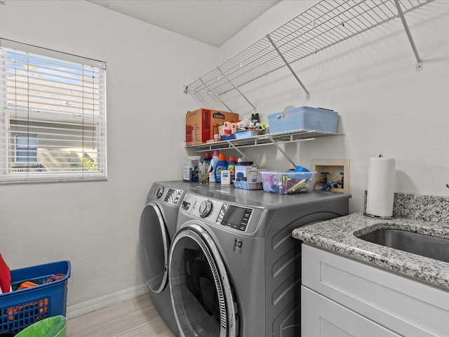 laundry room featuring a sink, light wood-style floors, baseboards, and washing machine and clothes dryer