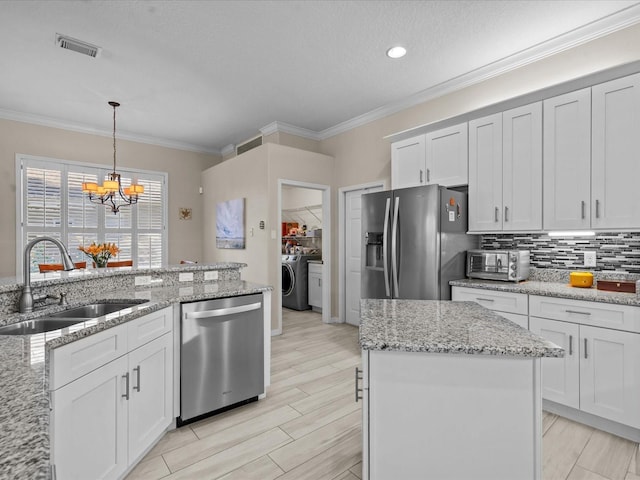 kitchen featuring visible vents, stainless steel appliances, an inviting chandelier, washer / clothes dryer, and a sink