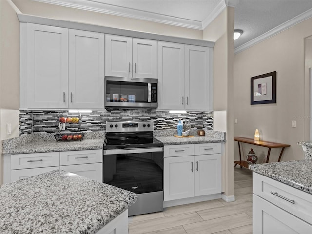 kitchen featuring light stone countertops, ornamental molding, decorative backsplash, white cabinets, and appliances with stainless steel finishes