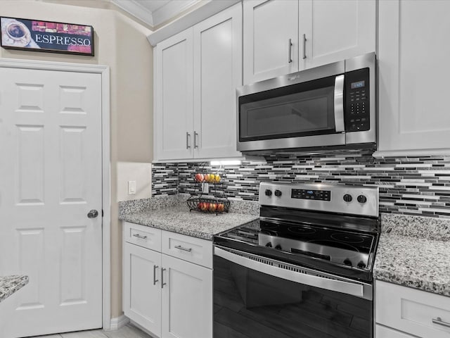 kitchen with light stone counters, stainless steel appliances, decorative backsplash, white cabinetry, and crown molding