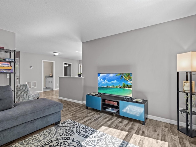 living room featuring visible vents, baseboards, and wood finished floors