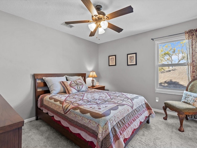 carpeted bedroom with visible vents, baseboards, a textured ceiling, and a ceiling fan