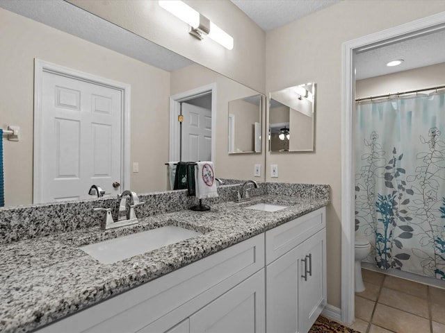 full bath featuring tile patterned flooring, double vanity, toilet, and a sink