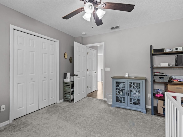 bedroom with carpet, visible vents, a closet, and a textured ceiling