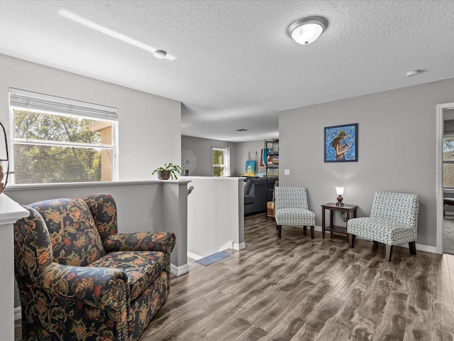 living area featuring an upstairs landing, a textured ceiling, baseboards, and wood finished floors