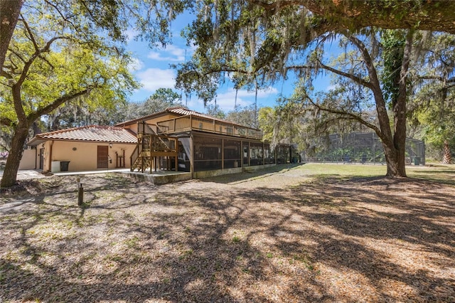 back of house with a patio, a tiled roof, a sunroom, and stucco siding