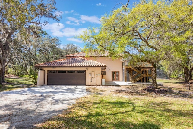 mediterranean / spanish-style home with stucco siding, driveway, a tile roof, an attached garage, and stairs