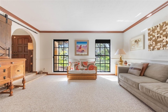 carpeted living room featuring a barn door, arched walkways, crown molding, and baseboards